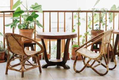 A balcony with rattan chairs, a wooden table and plants