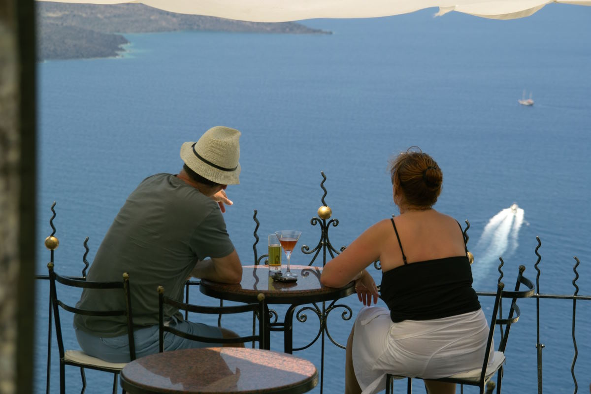 Two people sat at a table on a balcony, overlooking the sea
