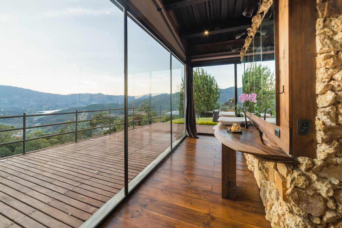 A photograph from the inside of a house, with a wooden balcony visible outside through a glass wall