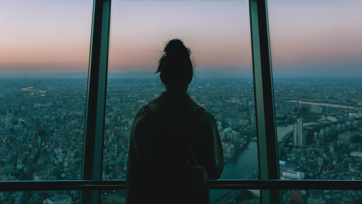 Person staring through window at city skyline