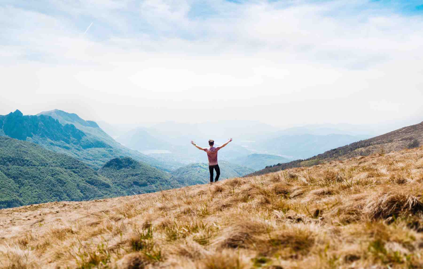 Man standing on hill with dried grass