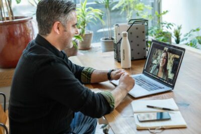 Man using MacBook Pro to take a video call with a woman