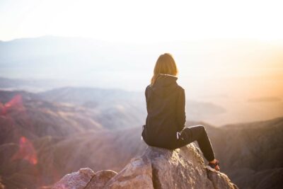 Woman sitting on a rock facing the mountains