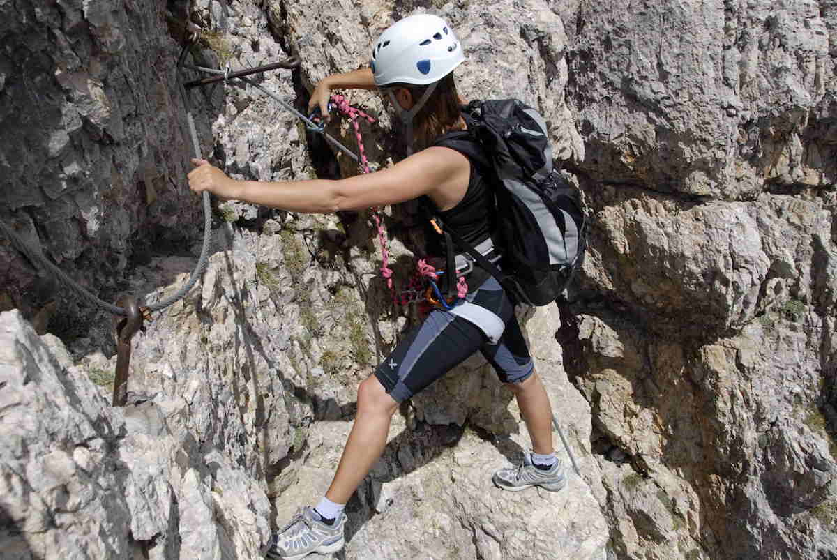 Woman traversing a rock face on a via ferrata