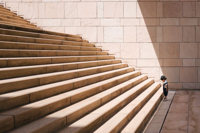 Young boy stood at bottom of stairs